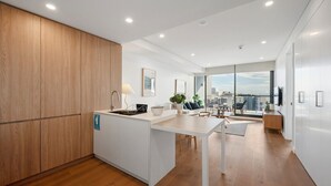 A modern kitchen with a central island, a dining area with a view, and a large window. - Oceanique Penthouse in Leighton Beach (North Fremantle)
