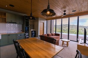 Una cocina moderna con armarios de madera, una mesa de comedor y un ventanal con vistas al exterior.