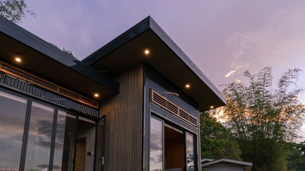 A modern house with a swimming pool, large sliding glass doors, and a covered outdoor seating area.