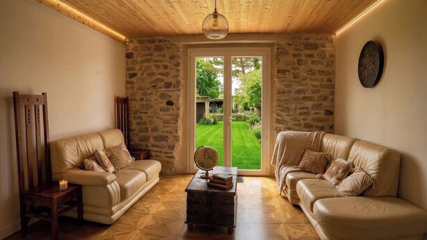 Ein Zimmer mit zwei Ledersofas, einem Holztisch mit Globus und einer Steinwand.