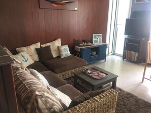 A living room with a sectional sofa, a coffee table, a bookshelf, and a television. - View of port and sea (Le Barcarès)