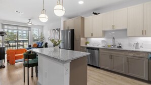 Una cocina moderna con encimeras de granito, electrodomésticos de acero inoxidable y armarios de madera clara.