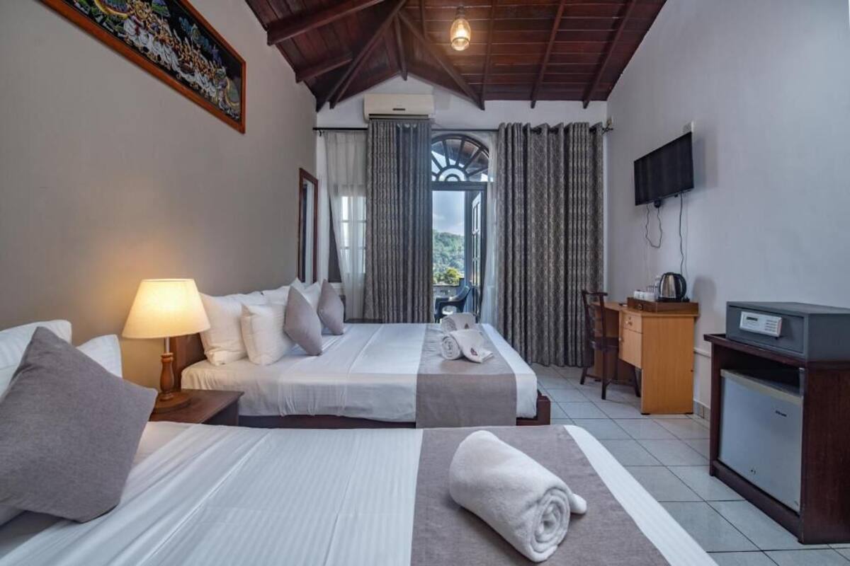Habitación de hotel con dos camas, un escritorio, un televisor y vistas al exterior.