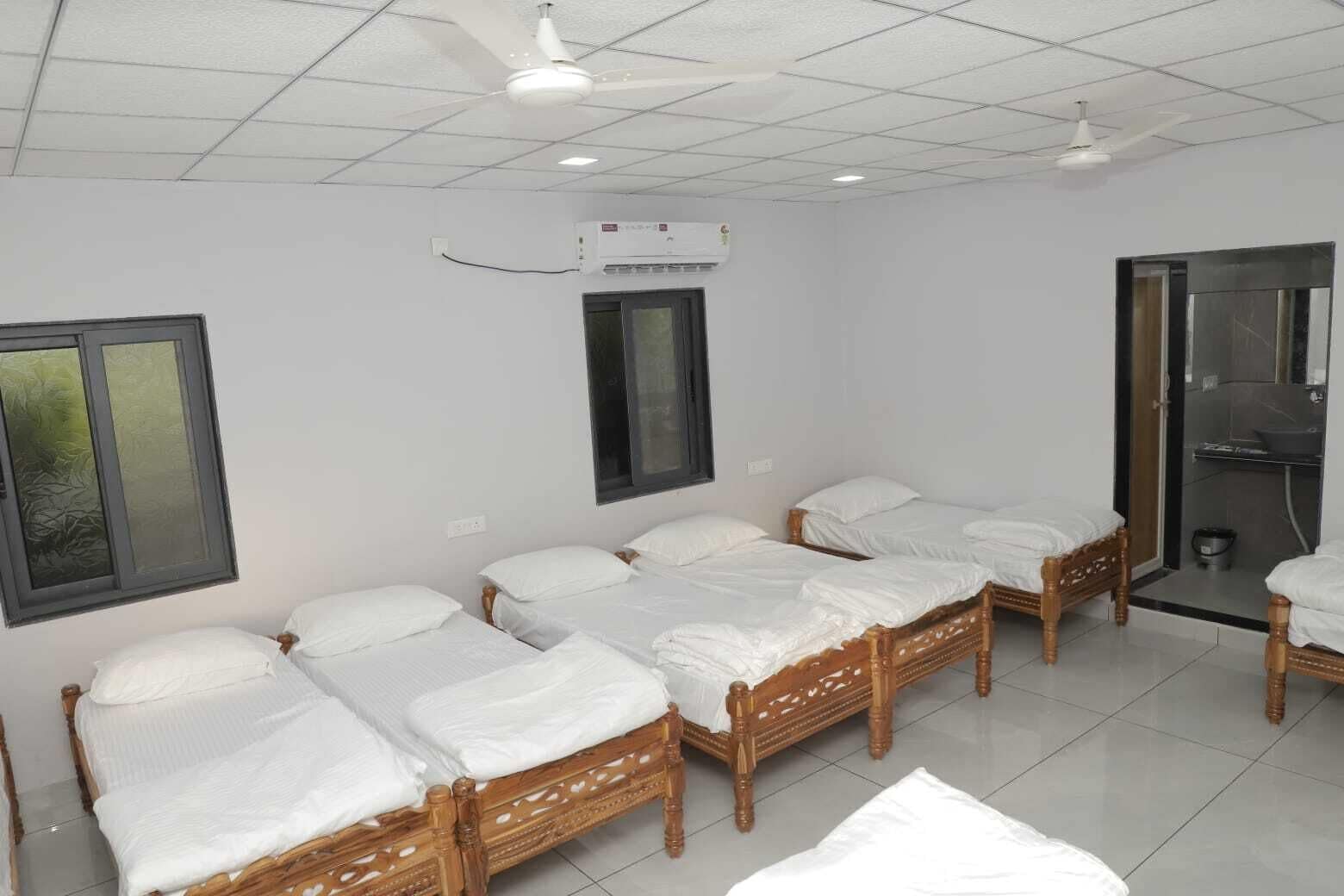 A hotel room with four wooden beds, a window, an air conditioning unit, and a shower area.