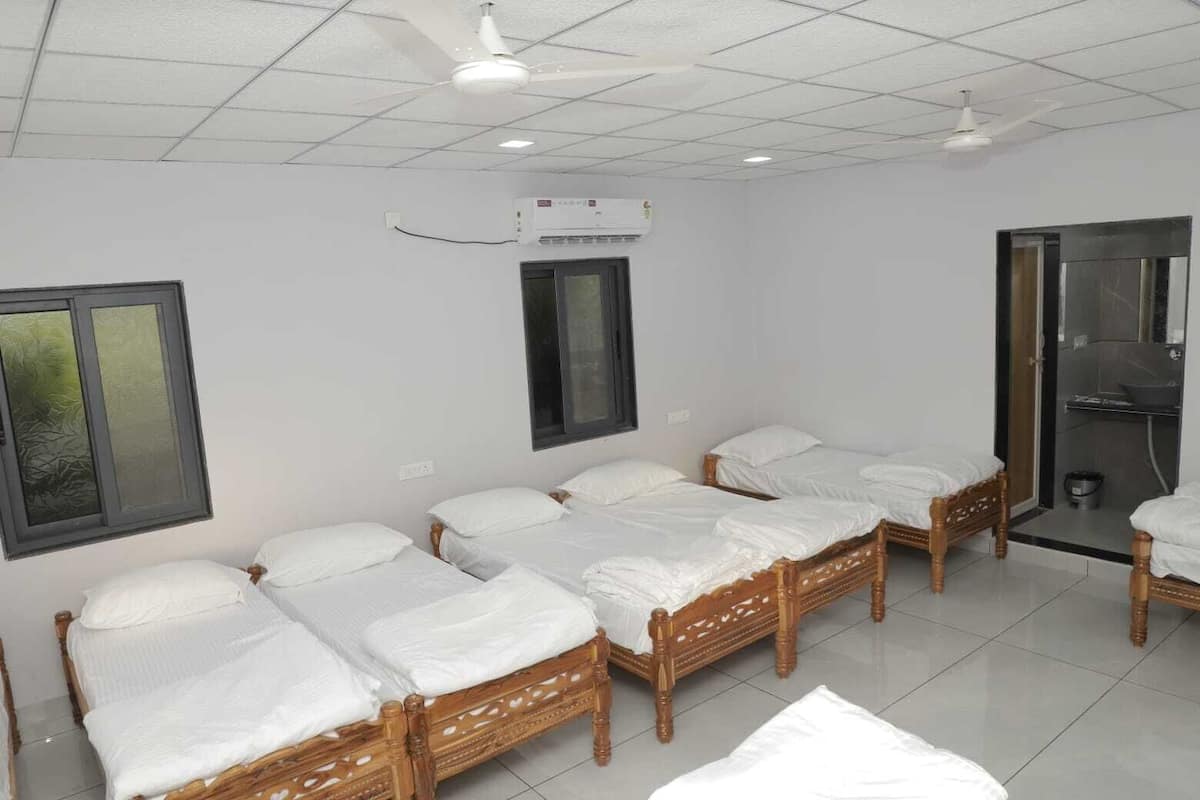 Une chambre d’hôtel avec quatre lits en bois, une fenêtre, un appareil de climatisation et un espace douche.