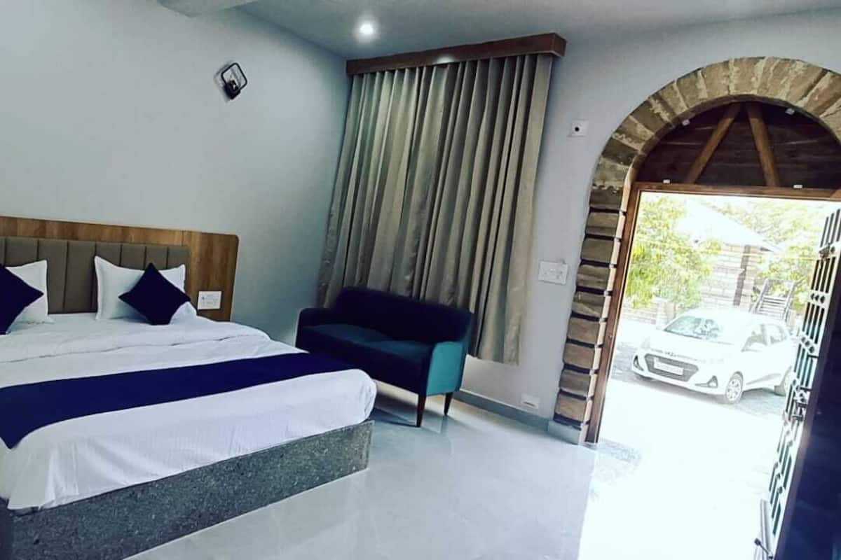 Quarto com cama, cadeira, arco de pedra e vista para um carro do lado de fora.