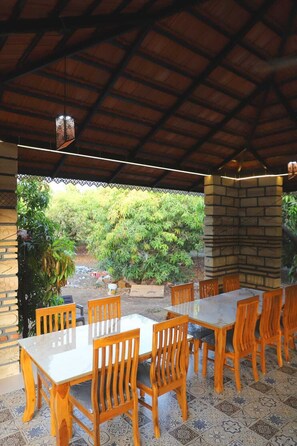 An outdoor patio with a brick wall, a tiled floor, and a table with chairs. - Gir Vintage Villa (Talala)