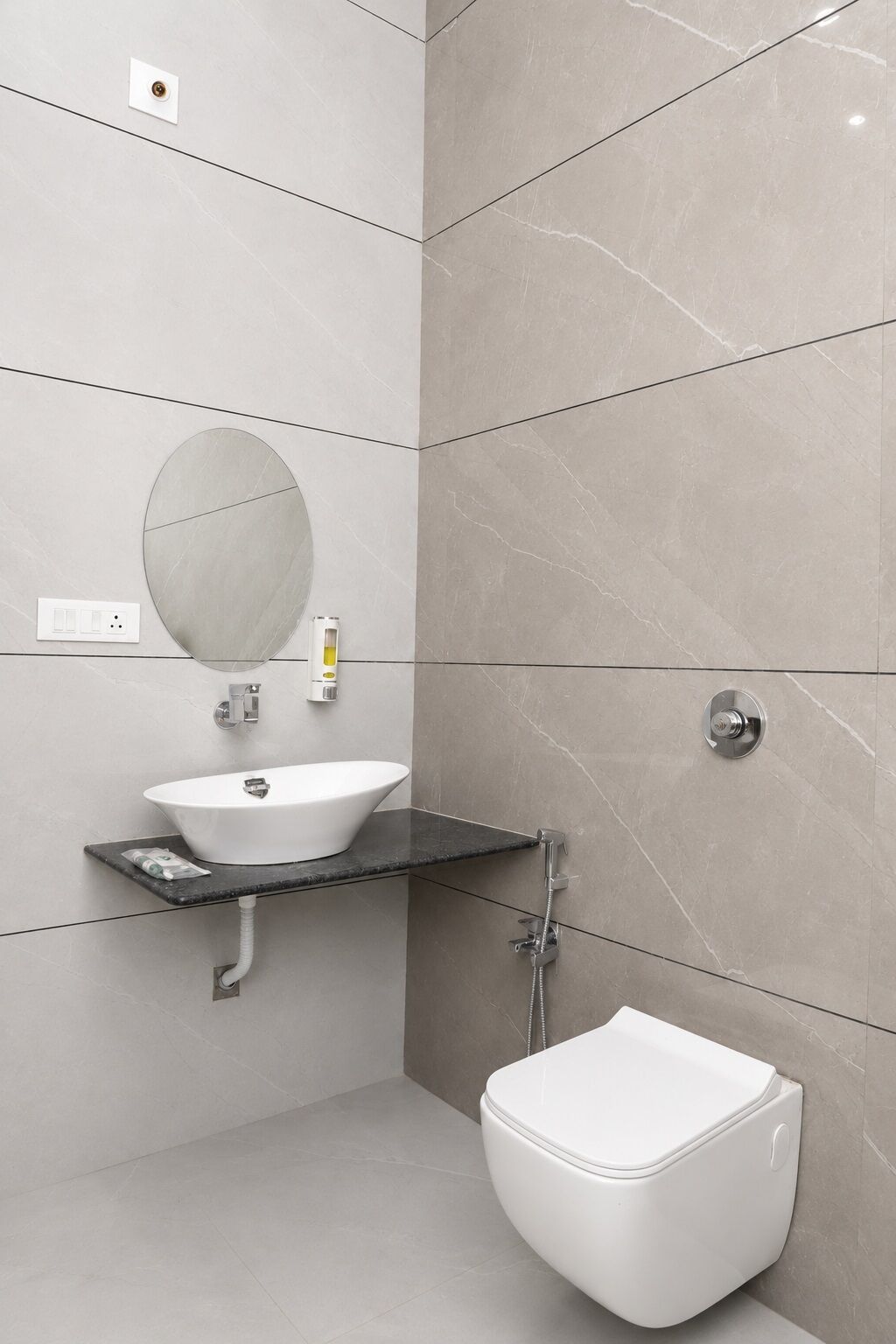 A modern bathroom with a white sink, a round mirror, a toilet, and a shower.