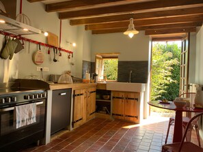 A kitchen with wooden cabinets, a built-in oven, a sink, and a window overlooking greenery.