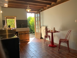 A kitchen with a sink, wooden cabinets, and a red chair.
