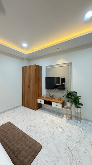 Un salon moderne avec une armoire en bois, un téléviseur à écran plat, un sol en marbre et un tapis marron.