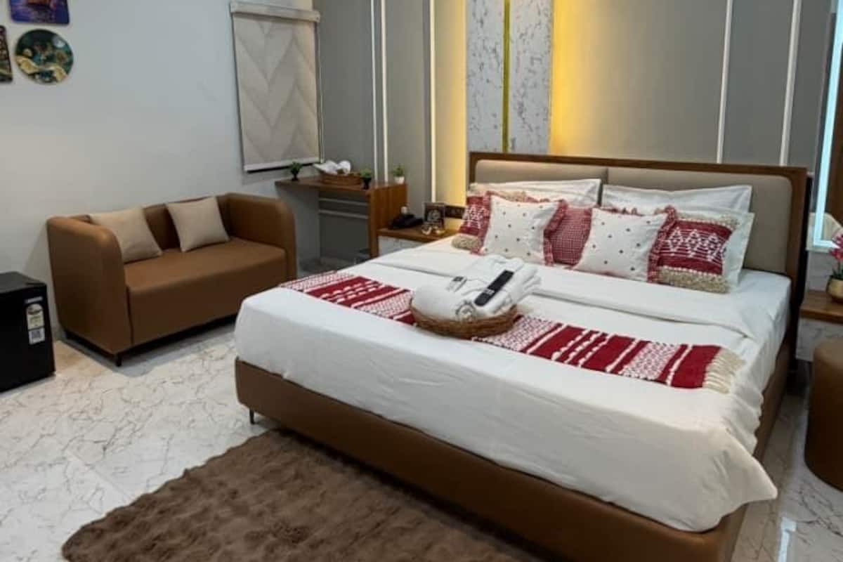 Quarto moderno com cama, sofá, ventoinha no teto e piso de mármore.