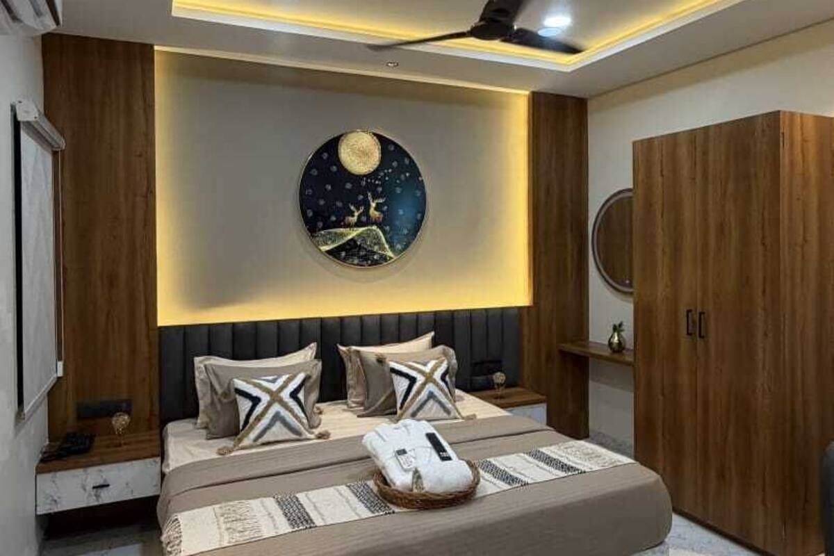 Quarto moderno com cama, mesas de cabeceira, ventoinha no teto e relógio fixado na parede.
