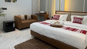 A modern bedroom with a bed, ceiling fan, air conditioning unit, and a brown rug. - Supreme Stays (Indore)