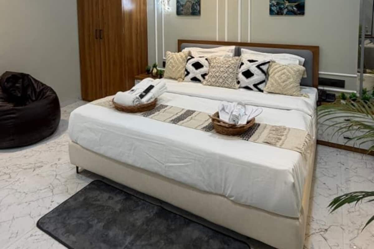 Quarto com cama, ventoinha no teto, mesas de cabeceira e guarda-roupa.