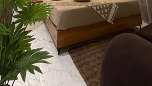 A bedroom with a bed, a ceiling fan, a large plant, and a curtain. - Supreme Stays (Indore)