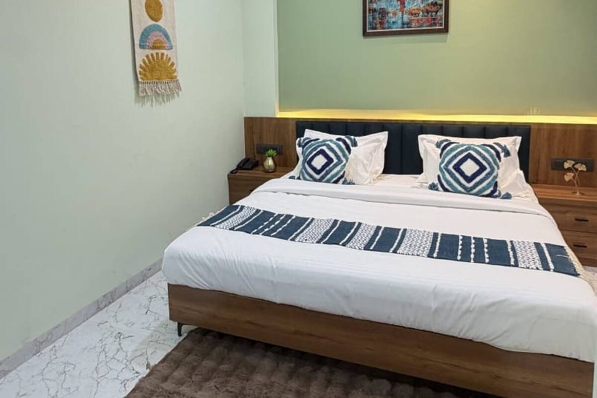 Quarto com cama, mesa de cabeceira, ventilador de teto, pintura e um adorno na parede.