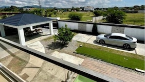 Zona residencial con un patio cubierto, una piscina y un coche blanco estacionado en la calle.