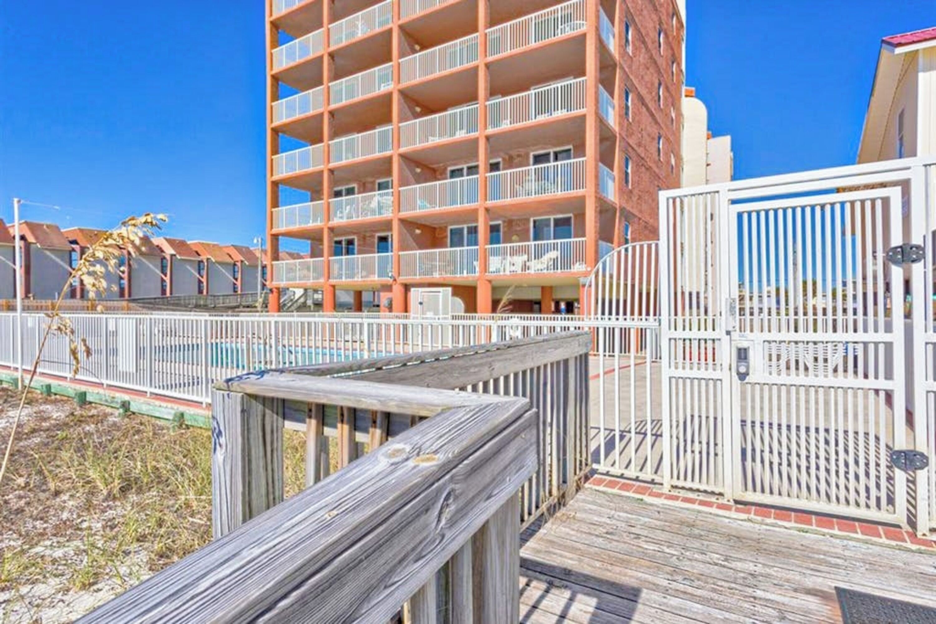 A multi-story hotel with balconies, a pool area, and a wooden boardwalk.