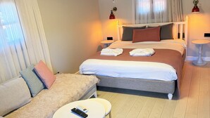A hotel room with a bed, a sofa, a small round table, and a ceiling fan. - Jasmine Suıts (ula)