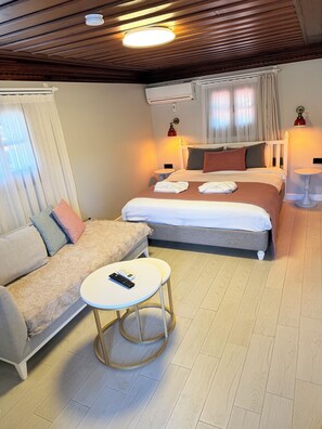 Une chambre dâhĂŽtel avec un lit, un canapĂ©, une petite table ronde et un ventilateur de plafond.