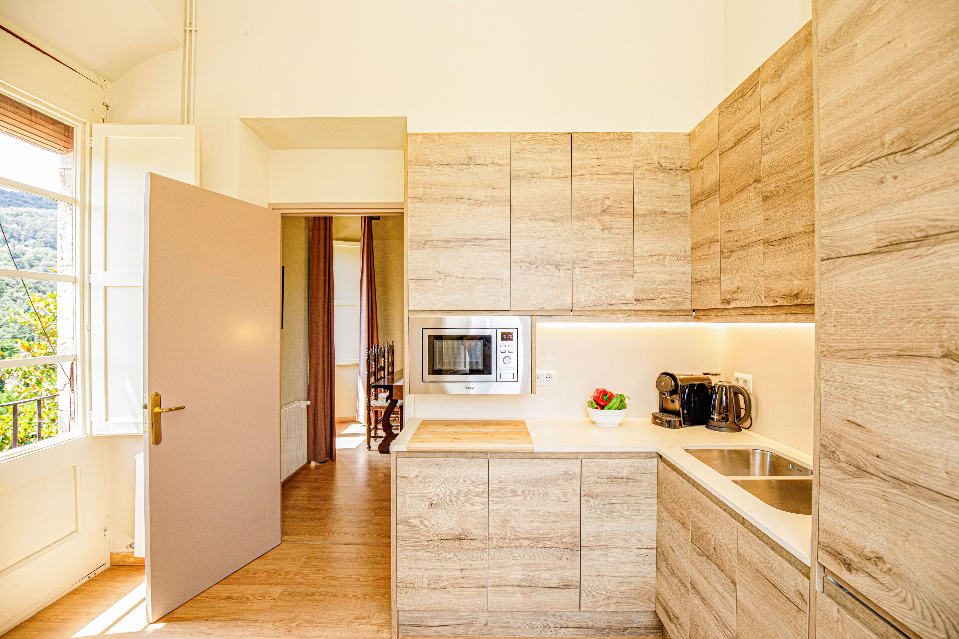 Una cocina moderna con microondas, lavamanos y muebles de madera.