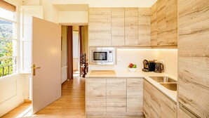 A modern kitchen with a microwave, sink, and wooden cabinetry. - LITTLE PALACE MIRADOR The best panoramic views (Besalu)