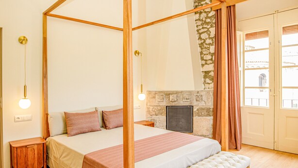A four-poster bed with a stone fireplace, wooden flooring, and a bench. - LITTLE PALACE MIRADOR The best panoramic views (Besalu)