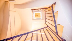 A spiral staircase with a metal railing, a small window at the top, and a white wall. - LITTLE PALACE MIRADOR The best panoramic views (Besalu)