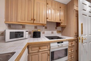 Eine Küche mit Holzausstattung, einer Mikrowelle, einem Toaster und einem Backofen.