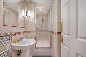 Ein Badezimmer mit Waschbecken, Spiegel, Dusche und einer Tür.