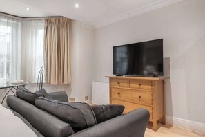 Ein modernes Wohnzimmer mit einer Couch, einem TV-Schrank aus Holz und einer Heizung.