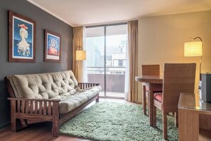A room with a sofa, a dining table with chairs, a green rug, and two wall-mounted lamps. - Apartment MUT - El Golf | City view and premium location in Las Condes (Las Condes)