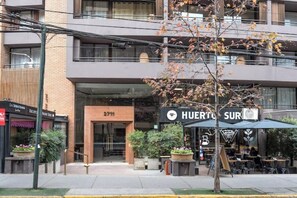 A multi-story building with a restaurant named 'Huerte Sur' on the ground floor. - Apartment MUT - El Golf | City view and premium location in Las Condes (Las Condes)