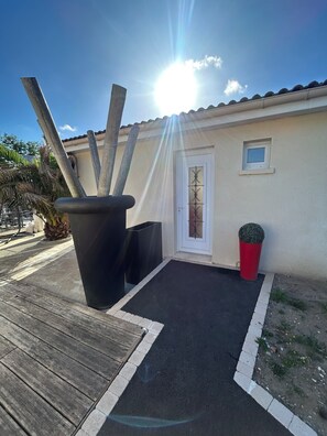 A building with a door, a small window, and a red cylindrical object. - La Providence (La Tremblade)