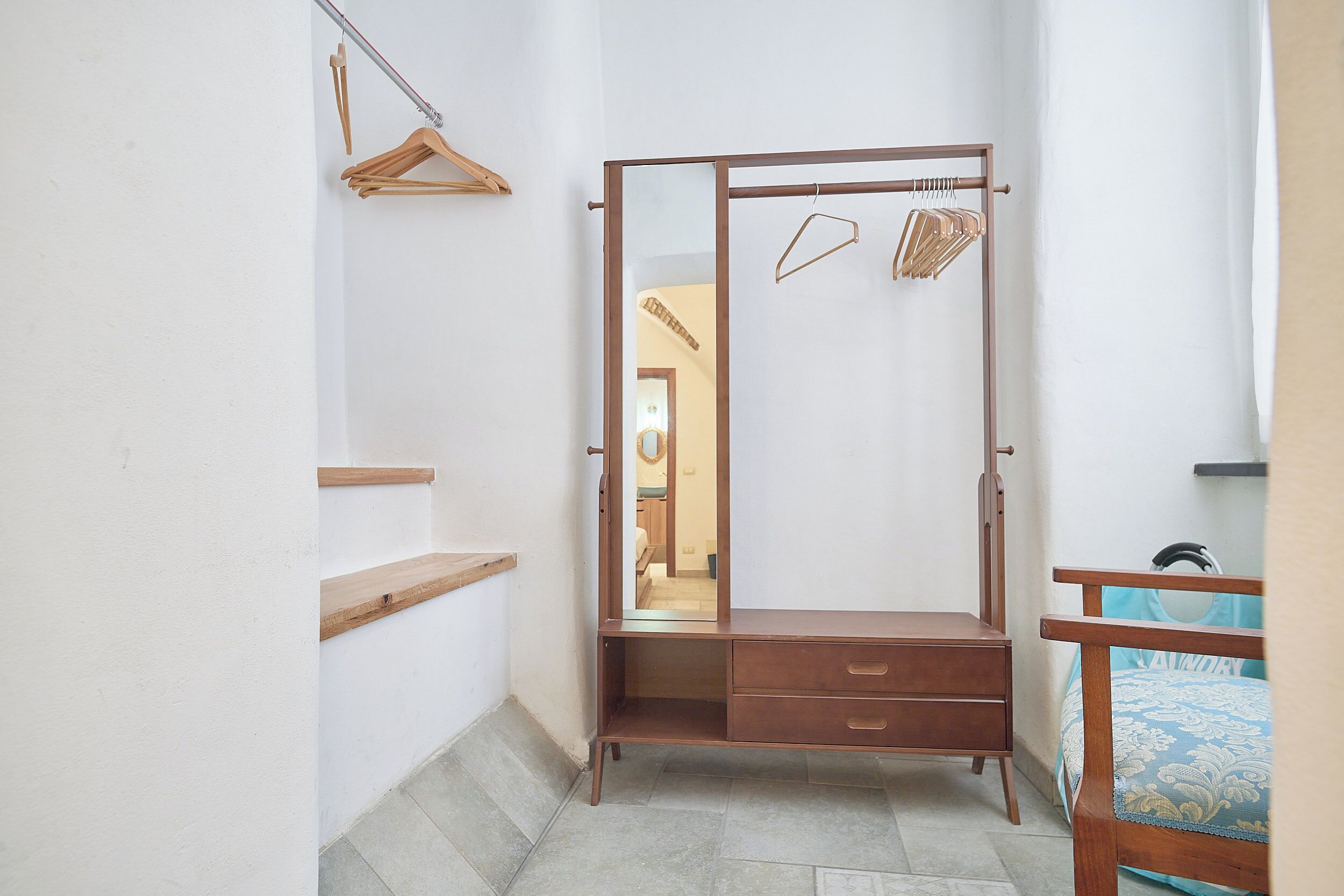 Un dormitorio con un armario de madera, una cama con colcha estampada y un espejo.