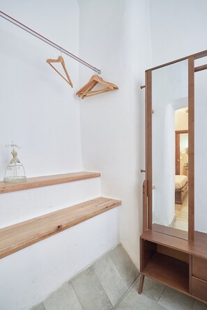 A room with a wooden bench, a mirror, and a wooden hanger on the wall. - La Dimora Blu (Albenga)