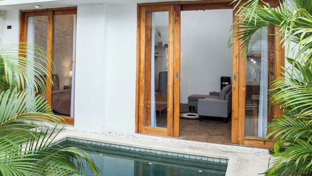 Una casa moderna de dos pisos con piscina, fachada de madera y ventanas grandes.