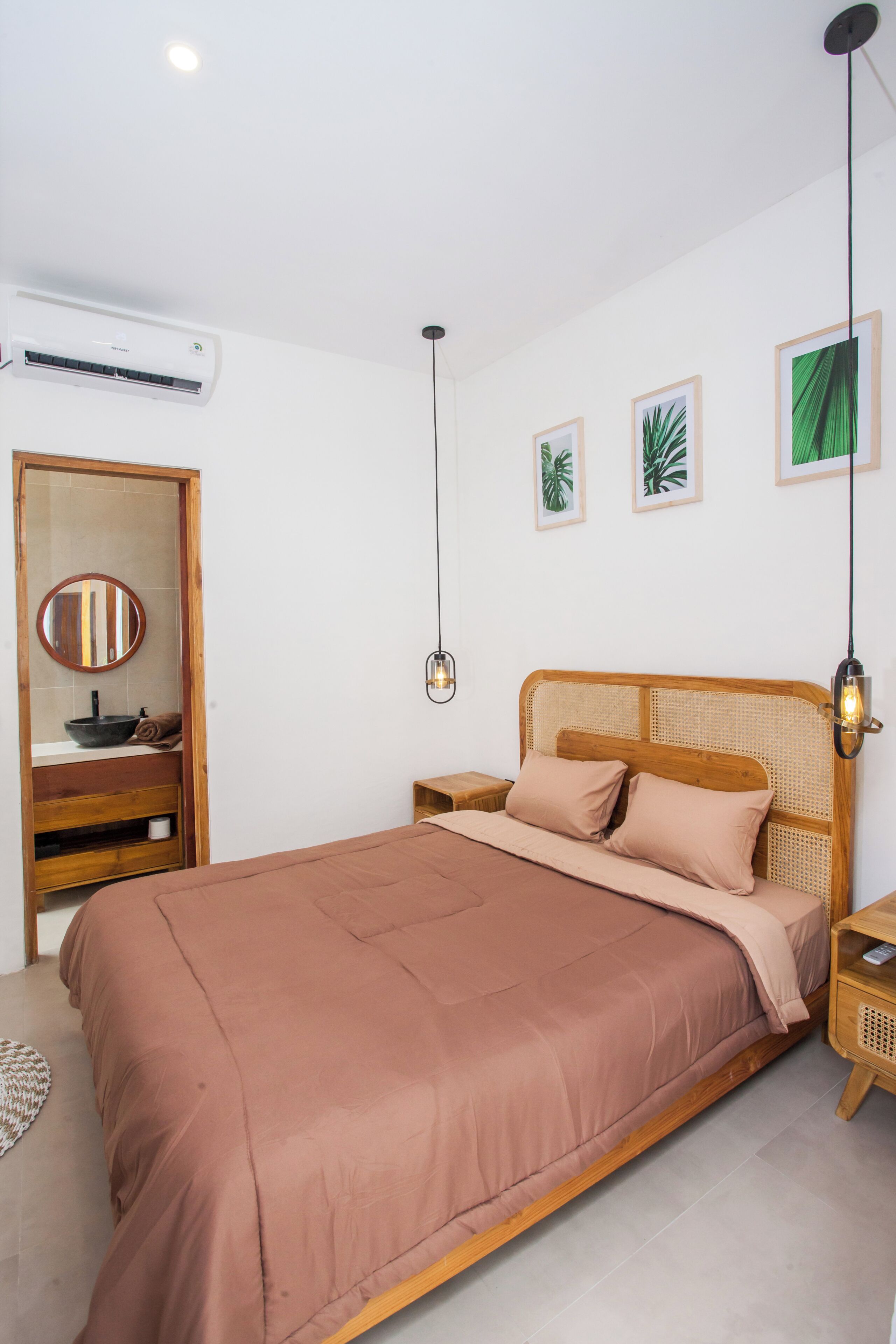 Un dormitorio con cama, mesita de noche, lavamanos y espejos, además de fotografías enmarcadas en la pared.