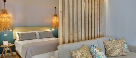 A bedroom with a bed, a sofa, a wooden wall panel, and two hanging lamps.