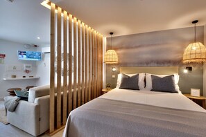 Une chambre d’hôtel moderne équipée d’un lit, de lampes de chevet, d’un téléviseur et d’une cloison en bois.