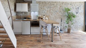 Una cocina moderna con armarios blancos, una mesa de comedor de madera y una pared de piedra.