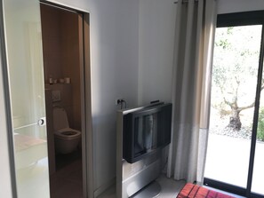 Une salle de bain équipée de toilettes, d’une douche et d’un téléviseur fixé au mur.