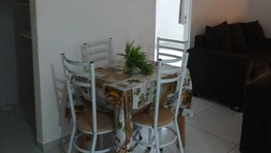 A dining area with a table and chairs, a potted plant, and a sofa in the background. - 2-bedroom apartment with air conditioning (João Pessoa)