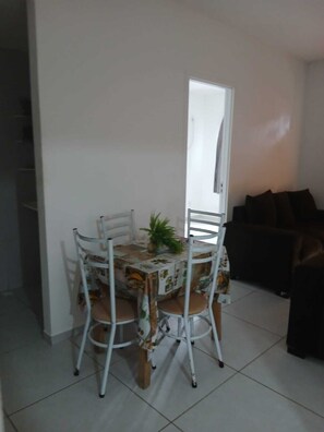 Un comedor con una mesa y sillas, una planta en maceta y un sofá al fondo.