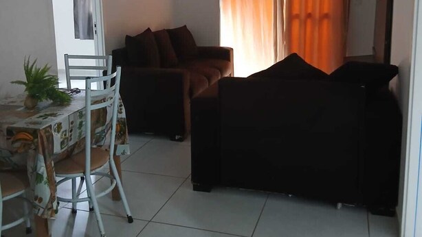 A living room with a dining table, chairs, a sofa, and a TV. - 2-bedroom apartment with air conditioning (João Pessoa)