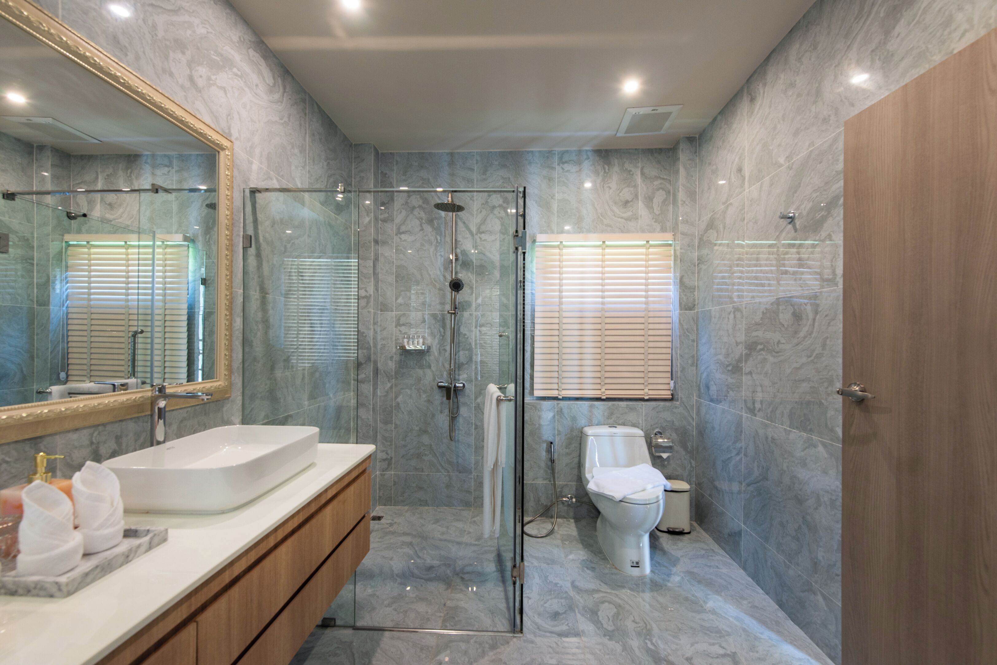 A modern bathroom with a glass-enclosed shower, a white sink, and a toilet.