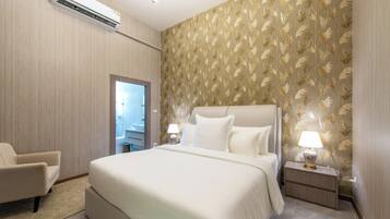 A hotel room with a large bed, two bedside tables with lamps, a chair, and an air conditioning unit.