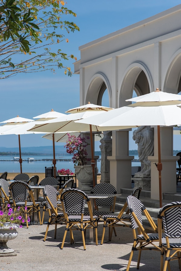 Outdoor seating with umbrellas, a statue, and a view of the water. - Kaysorn Siri (Sirindhorn)