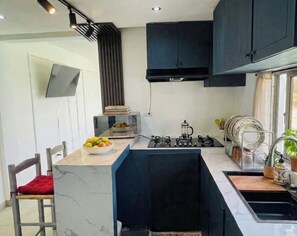 A modern kitchen with a marble countertop, black cabinets, and a built-in stove.